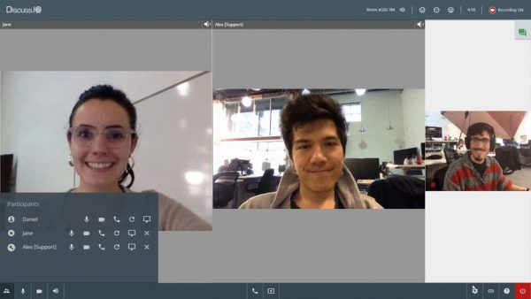 Three people in a video conference on Discuss.io. The main window shows two people smiling, and a smaller window on the right displays another person seated in an office setting.