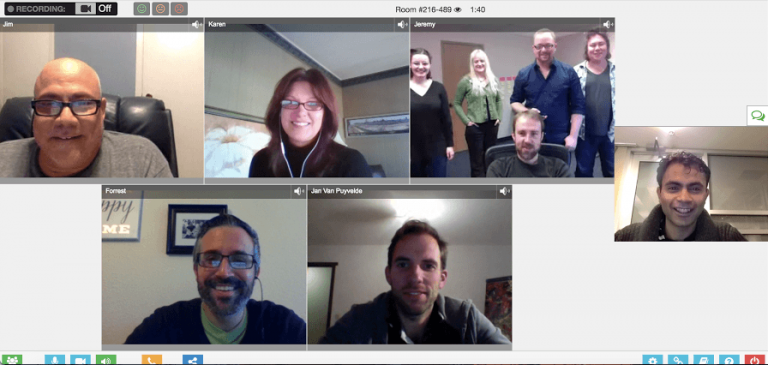 happy-people Video conference with eight participants in different windows, each smiling or looking at the camera. Multiple people are visible in some windows, with a casual background setting.