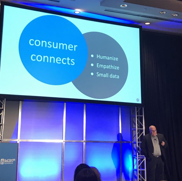 Person standing next to a presentation slide titled "consumer connects" with bullet points: Humanize, Empathize, Small data.