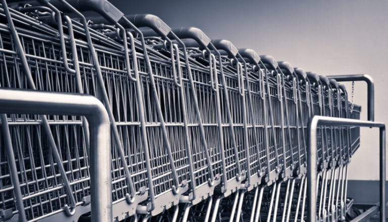 A row of neatly aligned empty shopping carts in a store's cart return area, viewed from the side.
