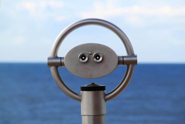 periscope-249150 Coin-operated binoculars facing the ocean with a clear blue sky in the background.