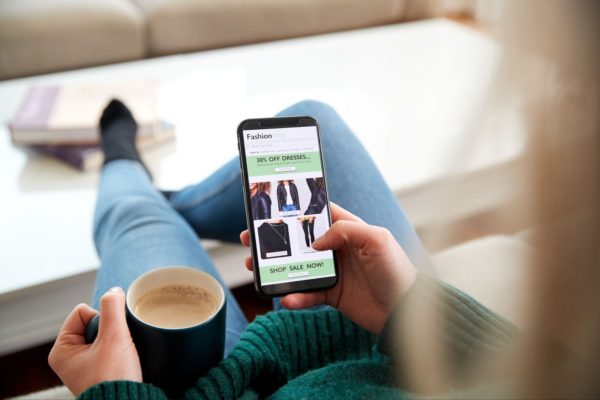 Shopping on a phone while drinking coffee