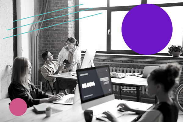 A black-and-white office scene with four people working on computers at desks. One person is standing, talking to a seated colleague. Colored graphic shapes overlay the image.