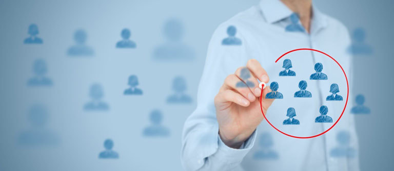 Marketing segmentation A person in a light blue shirt circles a group of blue human icons on a transparent screen, highlighting specific figures among blurred similar icons in the background.