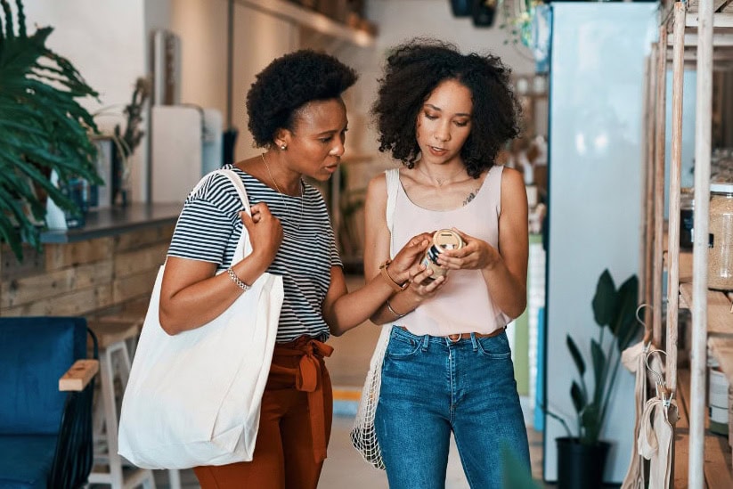 products-r-d Two people in casual clothes examine a product together in a store aisle, surrounded by plants and shelves.