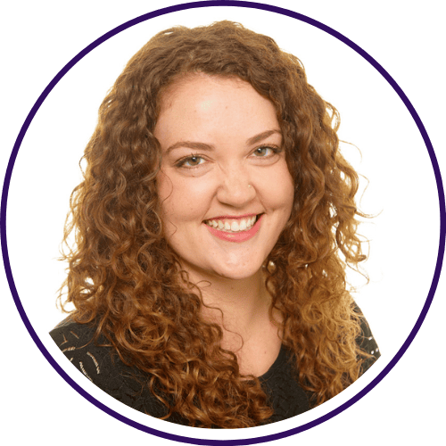 A person with curly hair smiles against a plain background, wearing a dark top, as if ready for a customer webinar.