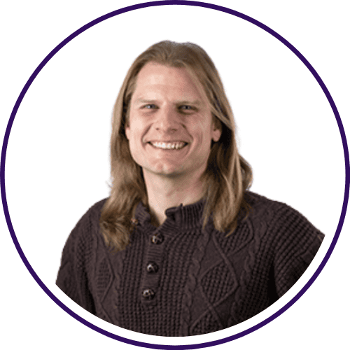 A person with long blonde hair is smiling, wearing a dark textured sweater, posed against a plain white background—confidently embracing the challenge of mastering GenAI.